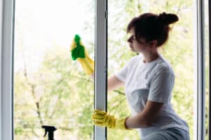 Brunette housewife cleaning big dirty window. Concept of housework and apartment service.